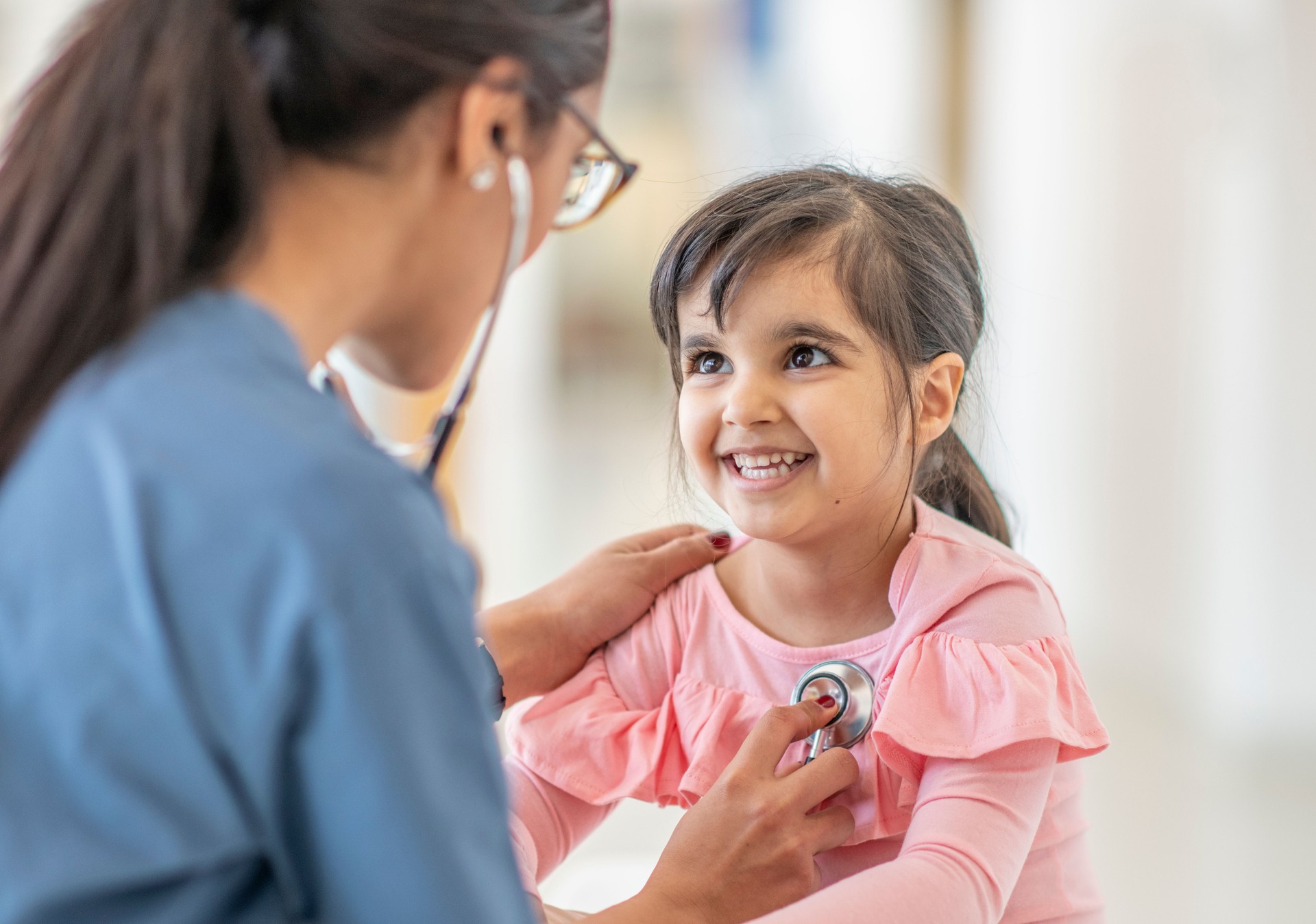 Female doctor checks girl's heartbeat
