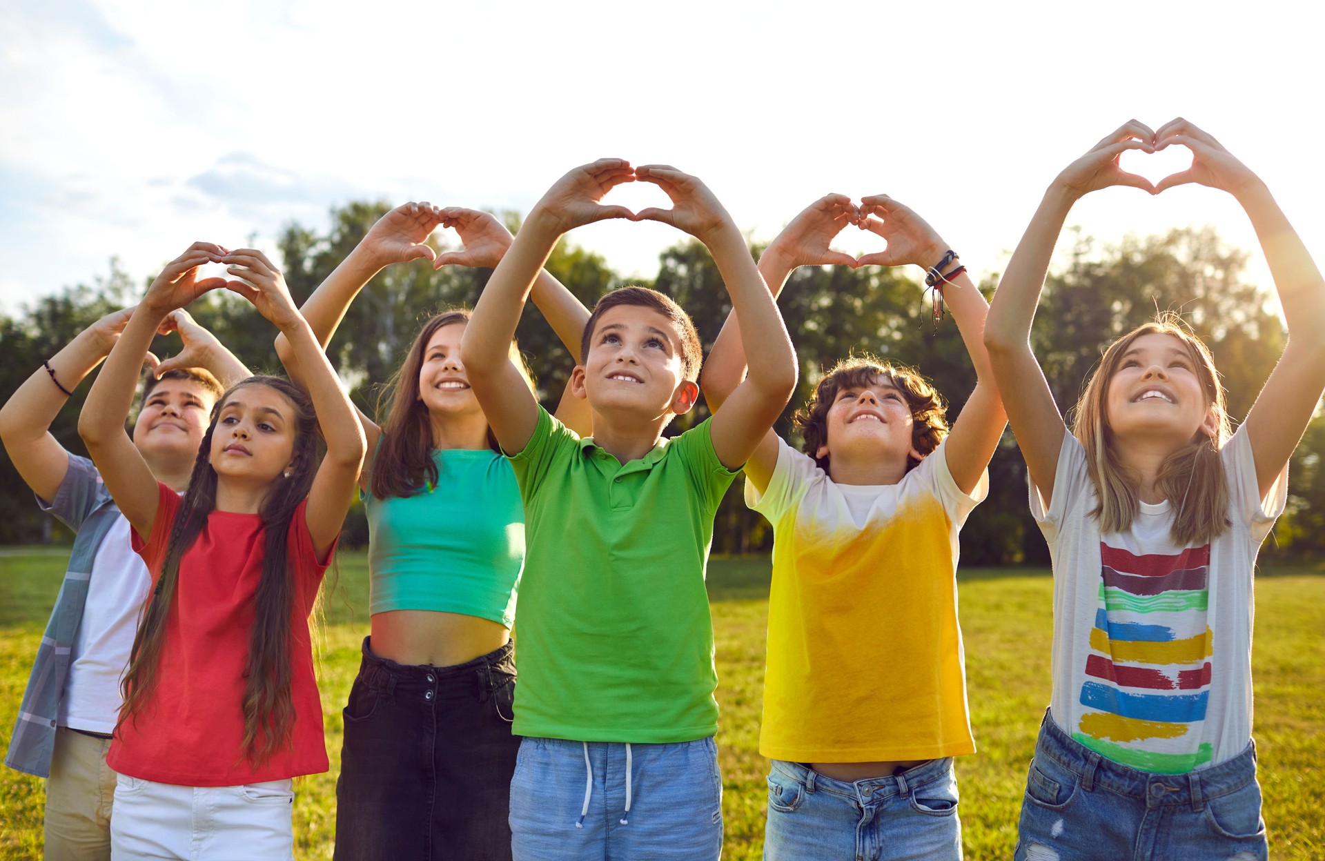 Happy children making heart shapes with their hands raised